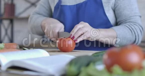 无法辨认的白种人高级妇女在围裙切番茄沙拉室内中年退休人员在视频的预览图