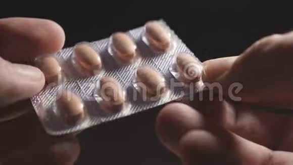 人手拿着药片在一个包裹在黑暗的背景上冠状病毒大流行近点视频的预览图