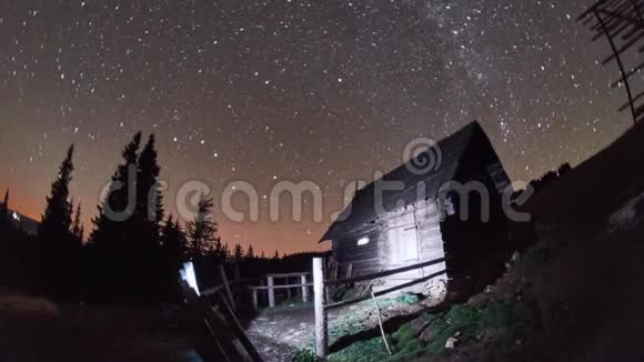 在冬天的夜晚牧羊人房子在星空下的奇妙景观的时间流逝视频的预览图