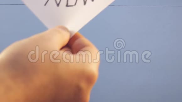 一个男人挂着一张白纸上面有黑色的铭文现在在蓝色的背景上视频的预览图