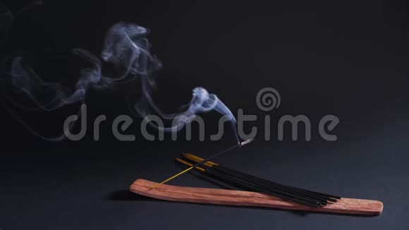 治疗东方烟芳香疗法放松和瑜伽香气棒的烟雾在黑色背景上移动视频的预览图