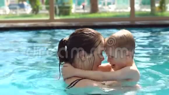 快乐的妈妈和她的小儿子在游泳池里游泳她吻了婴儿视频的预览图