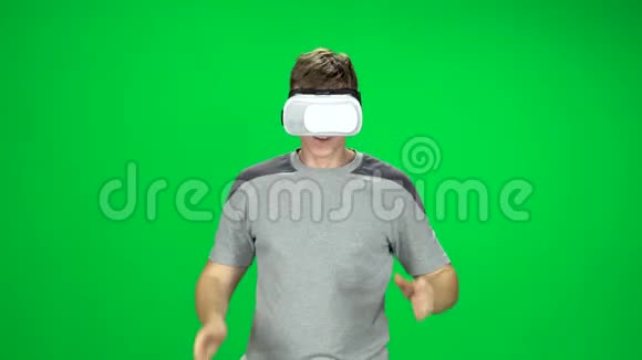 戴着虚拟现实耳机的微笑男人走向绿色屏幕视频的预览图