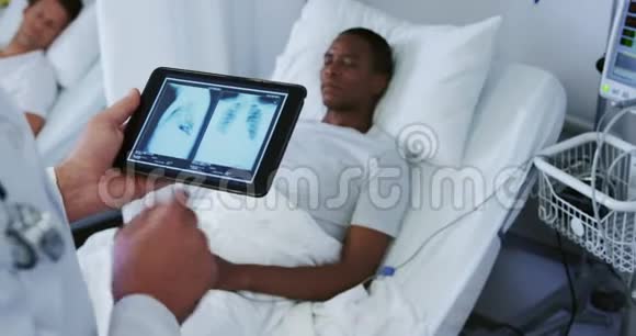 高加索男性医生在病房里检查数字平板电脑的x光报告视频的预览图