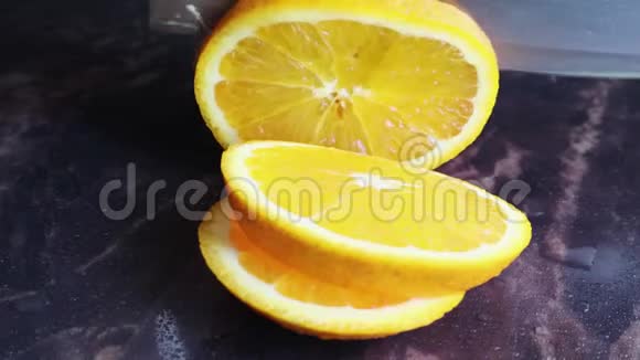 一只雌性的手在桌子上用一把刀切开了几片多汁的橘子家庭主妇在家厨房里切鲜橙f视频的预览图