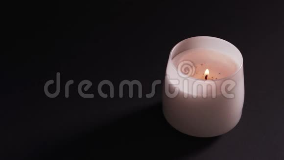 玻璃中的白色燃烧的蜡烛被隔离在黑暗的背景下放松和芳香疗法信仰的概念视频的预览图