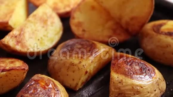 在金属锅上用香料和盐烤土豆片一块美味的烤土豆和叉子上的迷迭香视频的预览图