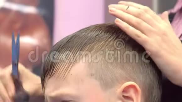 理发师要用剪刀在男孩头上剪刘海发型师双手特写视频的预览图