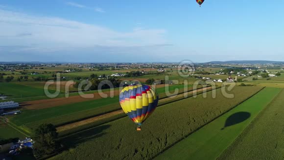 下午晚些时候的一个节日里一个热气球飘过农场的空中景色视频的预览图