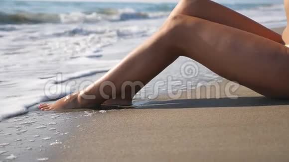 躺在热带海滩上的女人的苗条的腿和飞溅的波浪海水潮洗过晒黑的雌性脚少女视频的预览图