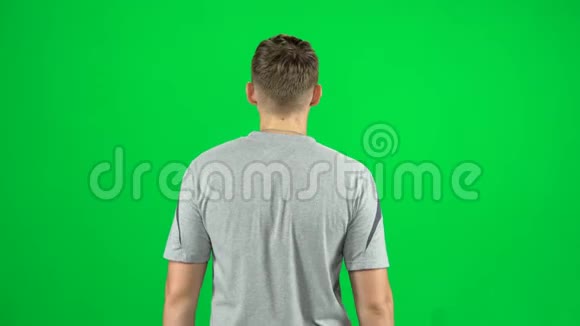 人在绿色屏幕上行走和问候的背面视图Chroma键视频的预览图