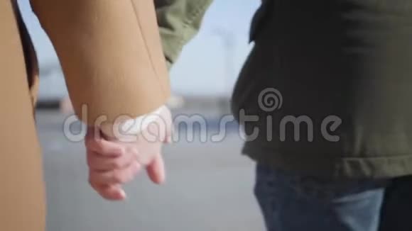 特写男女双手相握镜头跟踪年轻白人男女在户外行走视频的预览图