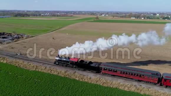 恢复蒸汽机在拉动古董乘用车的同时吹蒸汽和冒烟的空中角度视图视频的预览图