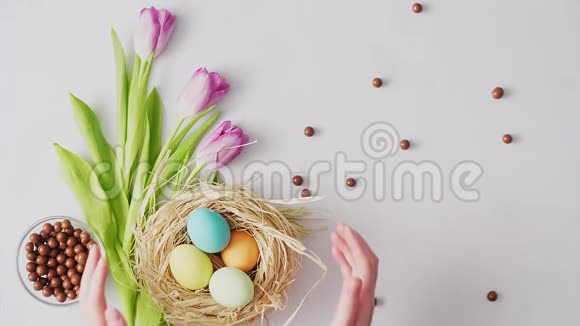 手拿起巢与彩色复活节彩蛋在明亮的背景复活节节日装饰品复活节概念背景视频的预览图
