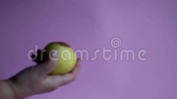 丑陋的水果腐烂的苹果在一只手上的粉红色背景储存条件差视频的预览图