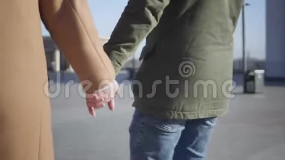 无法辨认的白种人男人和女人牵着手在阳光明媚的秋天在户外散步年轻夫妇约会视频的预览图