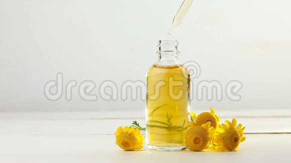 白色背景的黄色迷彩花在美丽的玻璃瓶中的精华视频的预览图