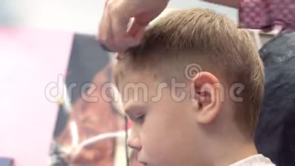 理发师用剪刀在男孩头上剪刘海面部特写侧视发型师他的手视频的预览图