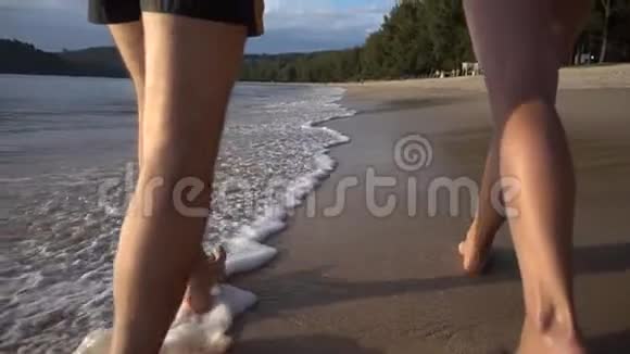 日落时分男人和女人沿着热带海滩散步每秒250帧慢动作视频的预览图