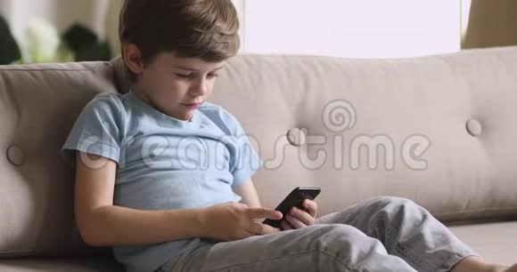 快乐可爱的学龄前儿童独自使用智能手机视频的预览图