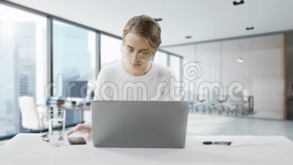 太忙了年轻女子坐在办公桌前用手机和写笔记白人女性视频的预览图