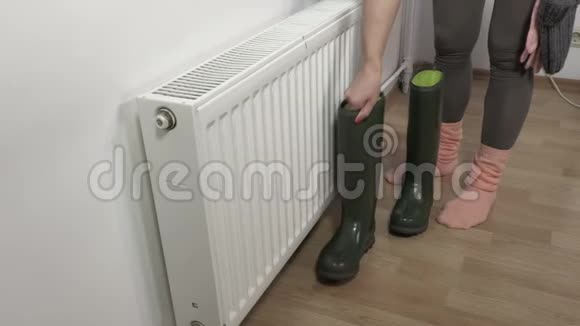 女人把靴子和衣服放在暖气片附近烘干视频的预览图