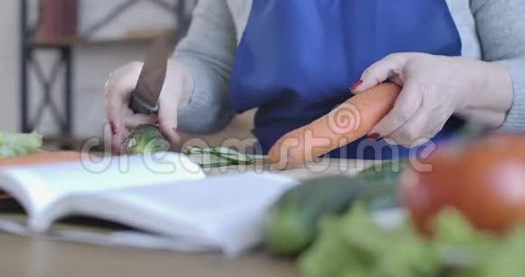 中年女性白种人用刀子剥胡萝卜为无法辨认的高级女性退休人员做饭视频的预览图