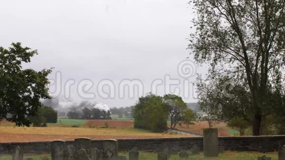 从墓地看到在多雾的雨天蒸汽机车用烟雾和蒸汽拉动货运视频的预览图