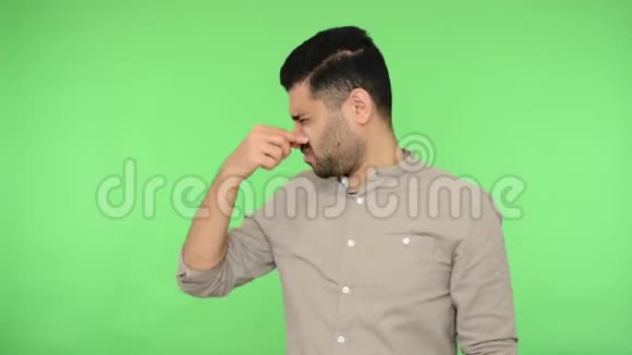 困惑的厌恶黑发男人捏着鼻子从糟糕的气味转向绿色背景色度键视频的预览图