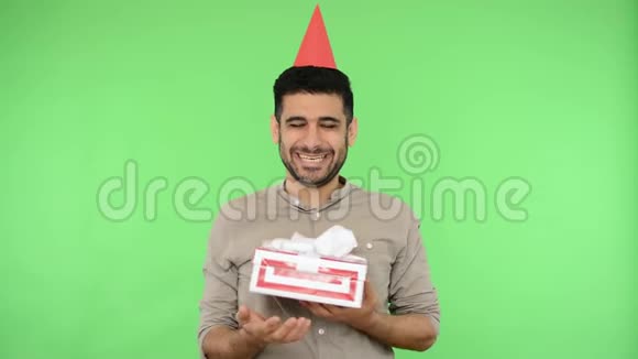 快乐的黑发男子与派对锥头和衬衫拥抱礼品盒绿色背景色度键视频的预览图
