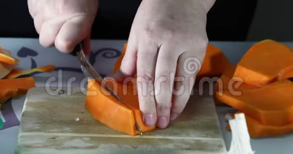 女人在厨房的木板上切南瓜女手准备奶油汤配南瓜健康饮食视频的预览图