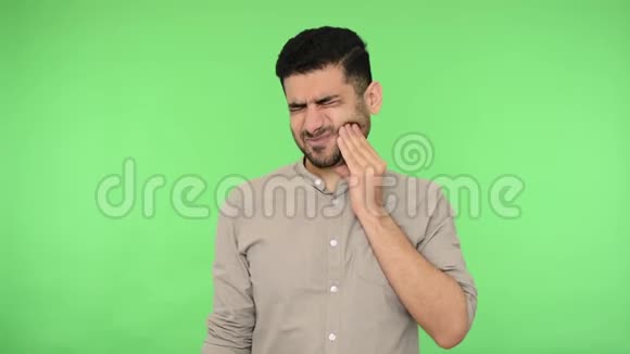 牙齿疼痛生病的黑发男子揉着脸颊闭着眼睛站着表情可怕地忍受着牙痛视频的预览图