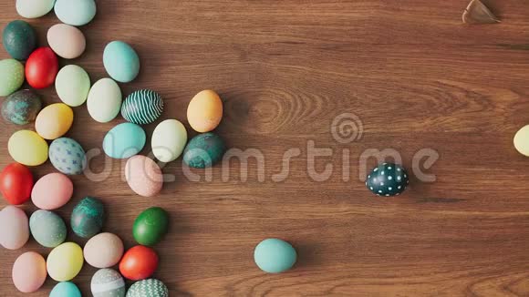 五颜六色的复活节彩蛋在木桌上滚动复活节节日装饰品复活节概念背景视频的预览图