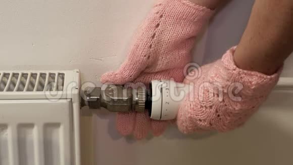 戴手套的女人在室内调节暖气片恒温器视频的预览图
