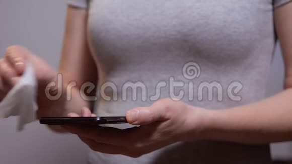 女人用湿布擦拭她的智能手机上的细菌视频的预览图