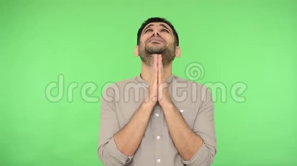 愁眉苦脸的黑发男子在祈祷中紧握双手用恳求的表情抬起头来绿色背景色度键视频的预览图