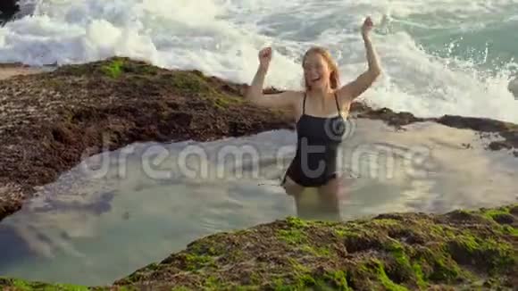年轻的女游客在巴厘岛潘泰泰加尔旺吉海滩的一个带有海水的天然小池塘里玩得很开心视频的预览图