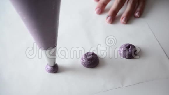 煮马卡龙糖果师把马克龙面团放在羊皮纸上烘焙女性制作蓝莓杏仁饼视频的预览图