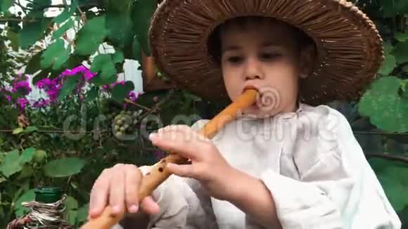近距离观看快乐有趣可爱的小男孩戴草帽尝试和学习吹木笛近距离观看视频的预览图