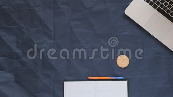 在蓝色背景皱巴巴的纸张复印空间上可以看到的笔记本电脑笔记本笔咖啡和饼干视频的预览图
