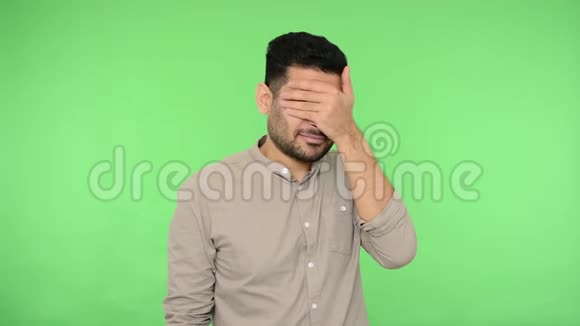 多情的黑发男人用手捂着脸用手指看着绿色背景色度键视频的预览图