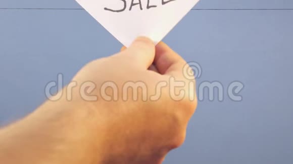 一个男人把一张白纸挂在蓝色背景上上面印着销售的黑色字样视频的预览图