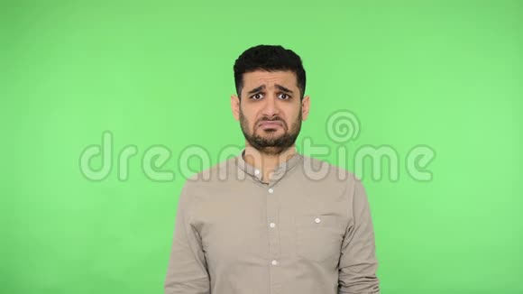 沮丧沮丧的黑发男子显示失败者的姿态看着相机与沮丧的表情绿色背景色度键视频的预览图