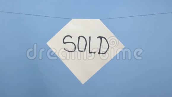 燃烧和吸烟的白色纸张与黑色铭文出售蓝色背景视频的预览图
