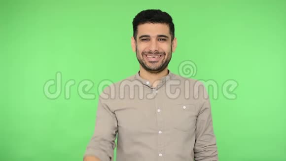 热情积极的黑发男子握手和友好的微笑工作室镜头绿色背景色度键视频的预览图