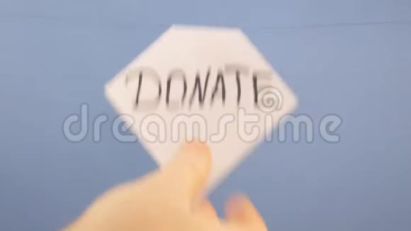 一个男人挂着一张白纸上面刻着黑色的字在蓝色的背景上捐赠视频的预览图