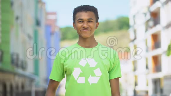 快乐的混血少年穿着回收标志t恤竖起大拇指生态视频的预览图