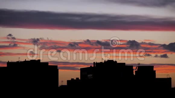 美丽的日落笼罩在阴影中的建筑物上蓝天粉红色和紫色的云视频的预览图