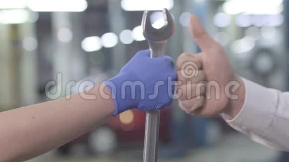 特写白种人的手在工作手套手握扳手和手显示拇指向上汽车技工及客户满意视频的预览图