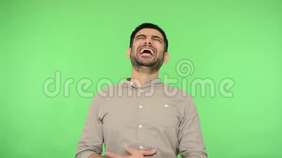 喜极而喜的黑发男子抱着肚子闭着眼睛大声笑出来绿色背景色度键视频的预览图